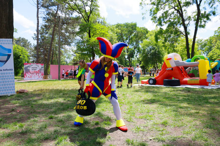 Colorful jester entertains at outdoor children's event with inflatable games. May 31, 2024 Balti Moldova.のeditorial素材