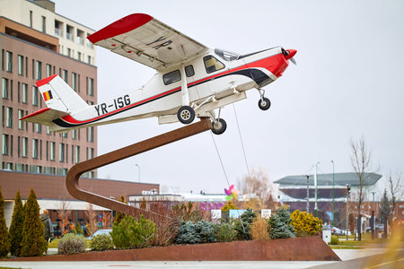 Small airplane display on curved sculpture in urban park setting. December 12, 2025 Brasov Romania.のeditorial素材