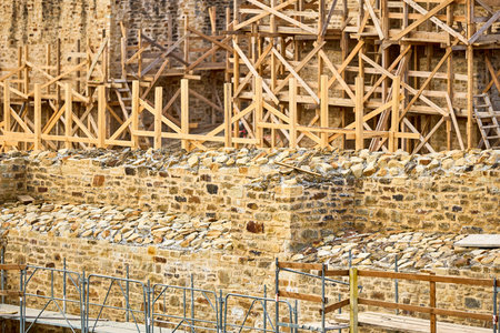 Medieval castle construction with stone walls and wooden scaffolding.の写真素材