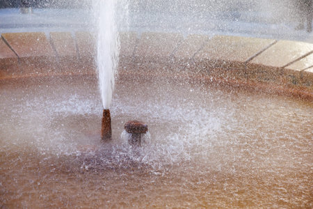 Vibrant fountain splashing water in urban setting on sunny day.