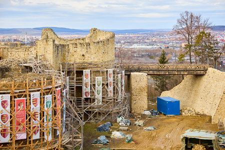 Historic stone castle restoration with cityscape view and wooden scaffolding. March 3, 2026, Suceava Romania.のeditorial素材