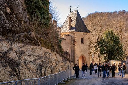 Tourists stroll near historic european castle tower in scenic landscape. March 19, 2025, Karlstejn,...