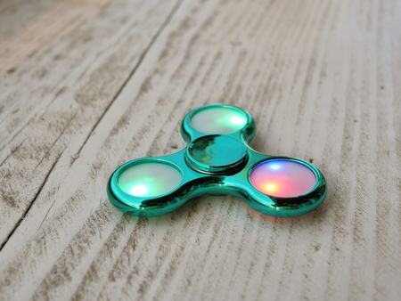 Popular fidget spinner toy on white wood backgroundの写真素材