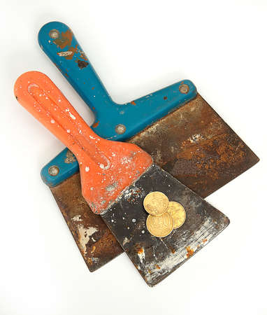 Old used spattle with coins on a white backgroundの写真素材