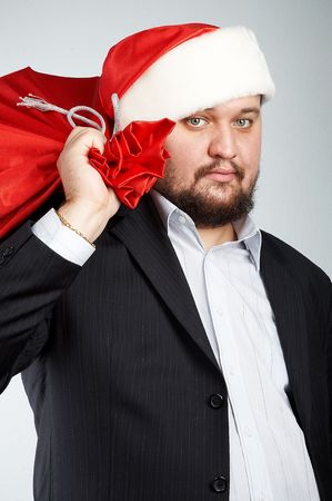 officially looking man with santa's hat and bag full of giftsの写真素材