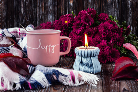 A pink cup of coffee, viva magenta asters, autumn grape leaves and a scarf. A gray candle is burning. happy autumn mood.の写真素材