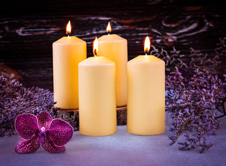 Spa still life with burning candles, orchid flowers and dried flowers on wooden backgroundの写真素材