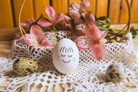 Easter egg with a smile. Around the Easter basket with quail eggs and pink alstroemerias. Easter mood.の写真素材