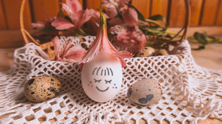 Easter egg with a smile. Around the Easter basket with quail eggs and pink alstroemerias. Easter mood.の写真素材