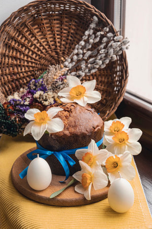 Ukrainian Easter cake. Around the yellow daffodils, a basket and a bouquet of willows and Easter eggs. Yellow and blue colors. side view.の写真素材