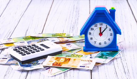 home loan concept. Euro banknotes, an alarm clock in the form of a house and a calculator on a white background. Investments in real estateの写真素材