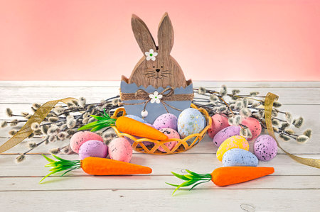 Easter bunny with easter eggs, carrot and willow and yellow ribbon. Festive Easter composition on a pink background.の写真素材