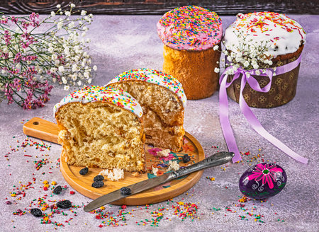 A cut Easter cakes on a tray is a traditional Ukrainian holiday baking. Knife, raisins, Easter eggs, sprinkles as decoration.の写真素材