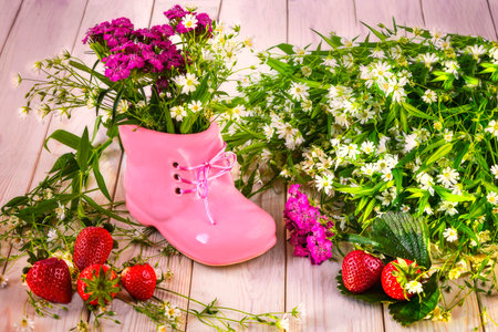 Pink shoe and bouquet of summer wildflowers, ripe red strawberries on the table. hello summer still lifeの写真素材