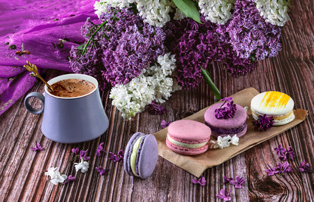 French macaroons and lilac flowers, cup of coffee on a wooden background.の写真素材