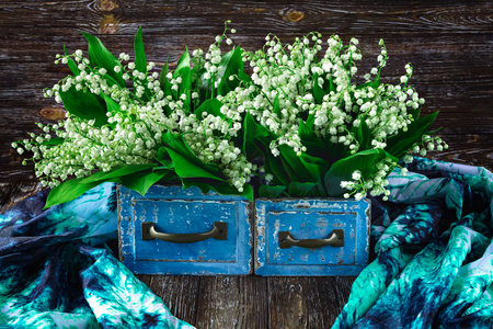Lily of the valley in a blue vantage box on a wooden backgroundの写真素材