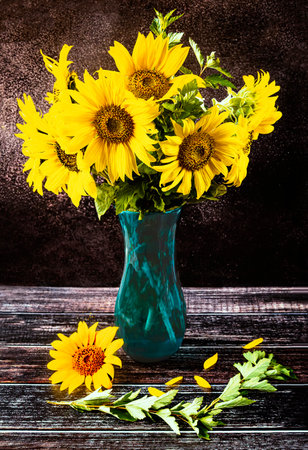A bouquet of sunflowers in a blue vase on a dark background in a rustic style. summer still lifeの写真素材