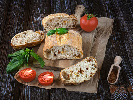 Ciabatta bread with basil, tomatoes and spices on wooden backgroundの写真素材