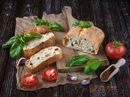 Italian ciabatta bread with basil, tomatoes and garlic on wooden backgroundの写真素材