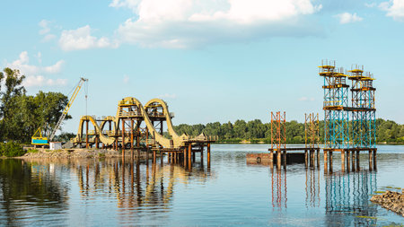 View of the construction of a bridge over the Dnipro River with construction structures and a crane against a blue sky background.の写真素材