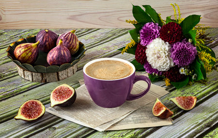 Fresh ripe figs on vintage plate, purple cup of coffee, bouquet of burgundy dahlias, purple shawl as decoration. Autumn still lifeの写真素材