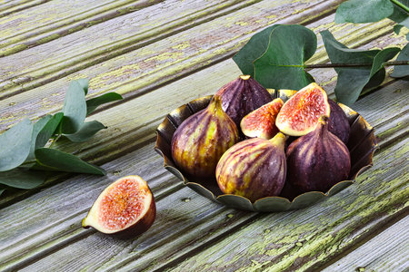 Fresh ripe figs in vintage plate, sprigs of green eucalyptus as decoration. Close up viewの写真素材