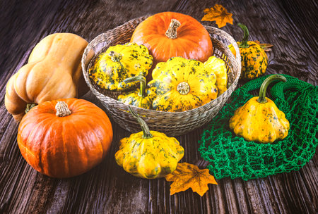 Colorful pumpkins in a basket on a wooden background. Autumn harvest.の写真素材