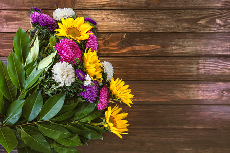 Bouquet of autumn flowers background. Flowers of colorful asters and yellow sunflowers on a dark wooden background.の写真素材