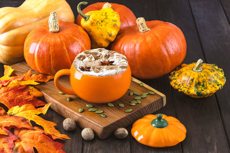 Pumpkin spice latte or cappuccino with whipped cream and pumpkin seeds on wooden background.の写真素材
