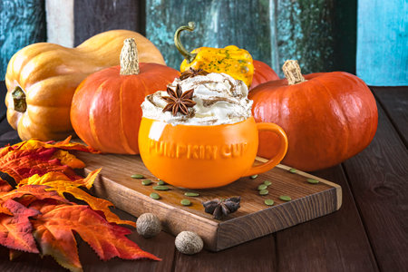 Pumpkin latte with whipped cream and spices on wooden backgroundの写真素材