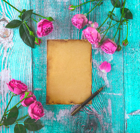 Old paper and pink roses on a turquoise wooden background.の写真素材