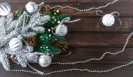 Christmas background with Christmas balls, silver garland and pine cones. Festive composition on a dark wooden background.の写真素材