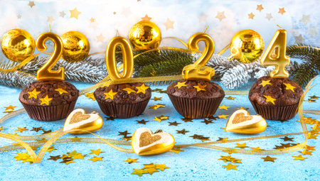 Christmas cupcakes with golden numbers 2024 and Christmas decorations on blue background