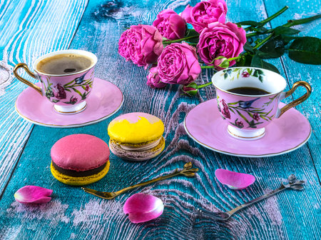 cup of coffee with macaroons and pink roses on wooden backgroundの写真素材