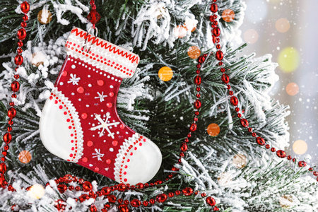 Glass red Christmas toy in the form of a sock on a snowy Christmas tree. Christmas card with bokehの写真素材