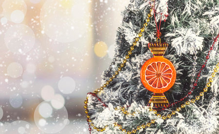 Glass Christmas ball in the form of an orange lollipop on a snowy Christmas tree. Christmas card with bokehの写真素材