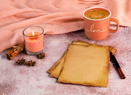 Romantic still life in the color of the year 2024 Peach Fuzz. A peach cup of coffee, kraft sheets of paper and an ink pen, a piece of peach-colored fabric.の写真素材