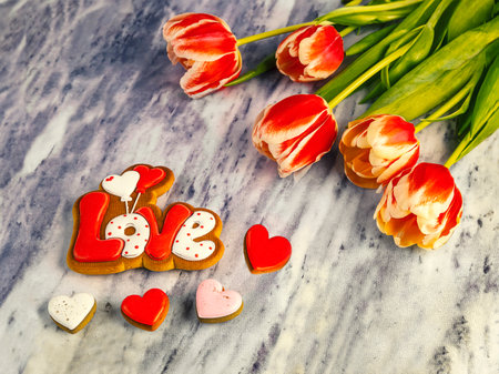 Bouquet of tulips and gingerbread cookies with the inscription love on a marble backgroundの写真素材
