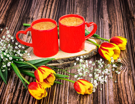 Two cups of cappuccino with tulips on a wooden backgroundの写真素材