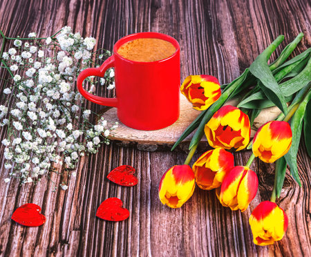 Cup of coffee with tulips and heart on wooden background.の写真素材