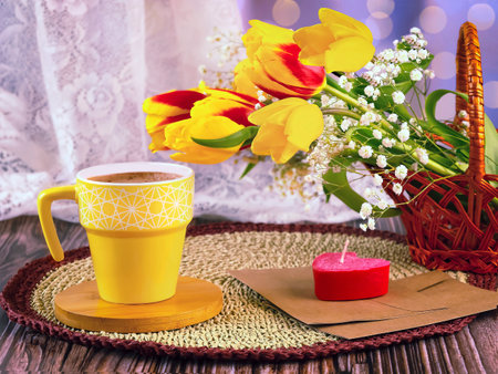 Cup of coffee, tulips and candle on a wooden tableの写真素材