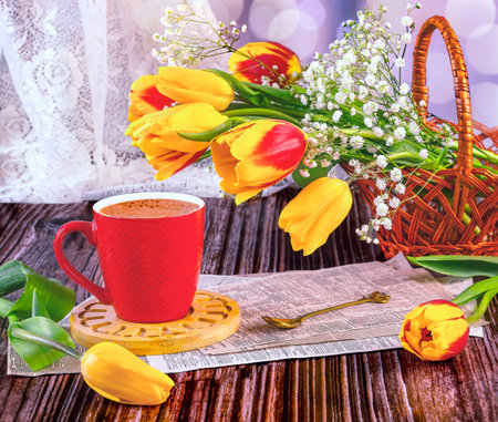 Cup of coffee with tulips and spring flowers on wooden backgroundの写真素材