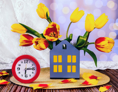 Bouquet of yellow tulips and alarm clock on a wooden tableの写真素材
