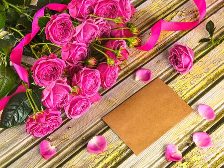 Bouquet of pink roses and blank card on a wooden backgroundの写真素材