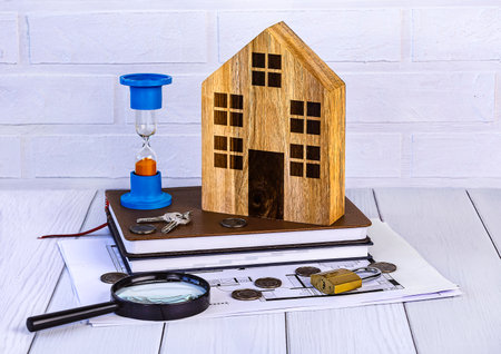 Wooden house model, magnifying glass, coins and hourglass. Home loan conceptの写真素材