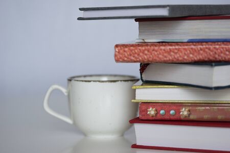 Stack of colorful books, open book and cup on wooden table. Back to school. Copy space