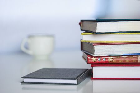 Stack of colorful books, open book and cup on wooden table. Back to school. Copy space