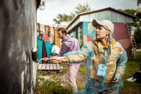 Girl street artist paints with a roller on the wall on Street Art Week festival on July 17, 2019 in...