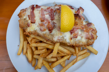 Wiener schnitzel with French fries on white plate