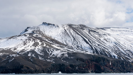 Rugged mountains with a dusting of snow at Deception Island, Antarcticaの写真素材